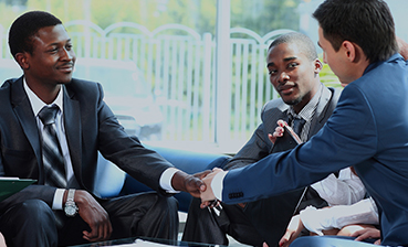 Business meeting: Three men in suits shake hands, reaching a deal.